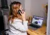 a woman sitting at a desk with a laptop and a phone