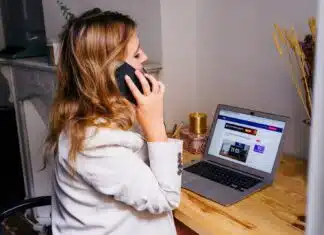 a woman sitting at a desk with a laptop and a phone